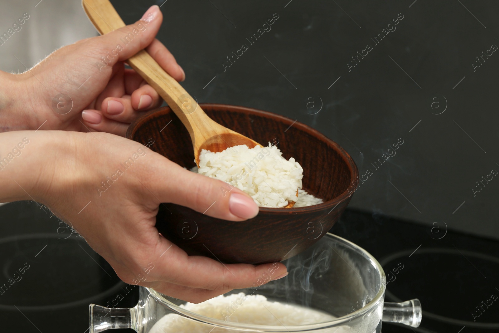 Photo of Woman taking boiled rice into bowl, closeup