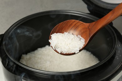 Taking boiled rice with wooden spoon on grey background, closeup