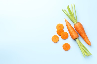 Whole and cut fresh carrots on light background, flat lay. Space for text