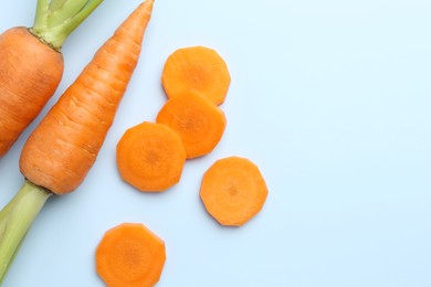 Photo of Whole and cut fresh carrots on light background, flat lay. Space for text