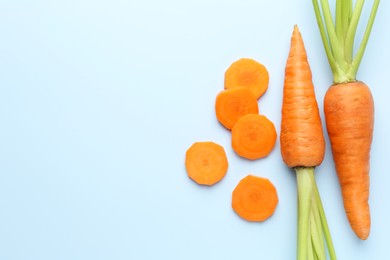 Photo of Whole and cut fresh carrots on light background, flat lay. Space for text