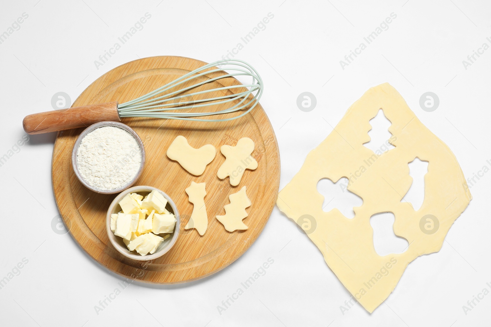 Photo of Raw dough, cookies, whisk and ingredients on white background, flat lay