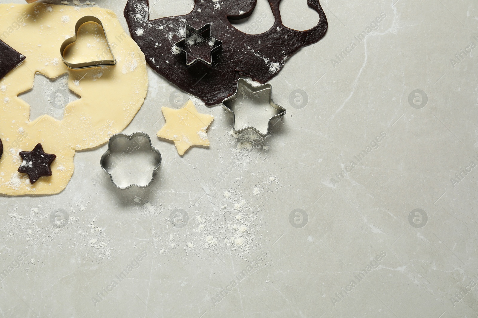 Photo of Raw doughs and cookie cutters on light marble table, flat lay. Space for text