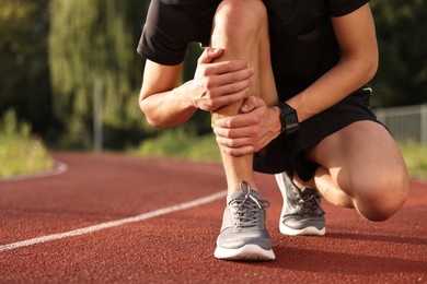 Photo of Sportsman with leg injury suffering from knee pain at stadium, closeup. Space for text