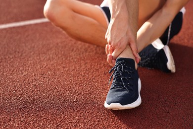 Sportsman with injured leg at stadium, closeup. Space for text