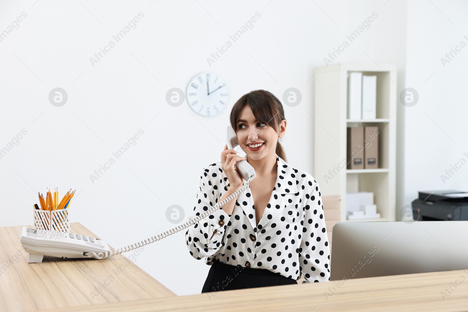 Photo of Portrait of receptionist at wooden desk in office