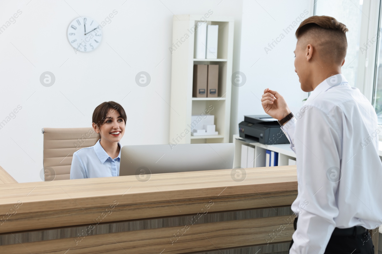 Photo of Professional receptionist working with client in office