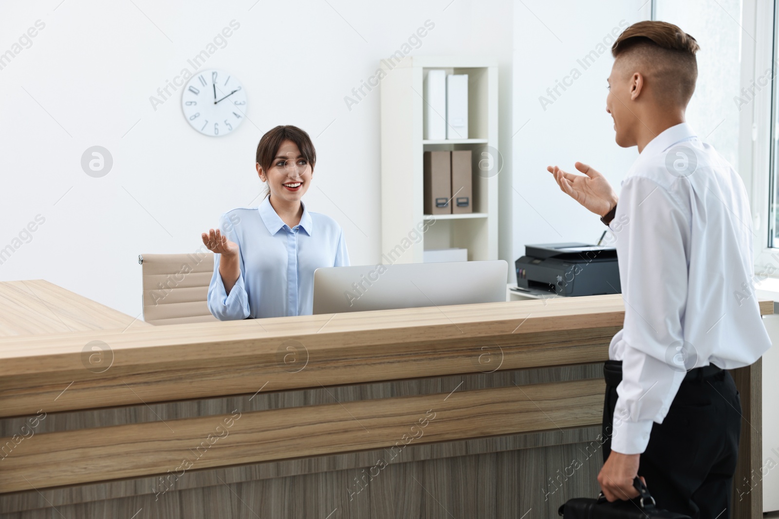 Photo of Professional receptionist working with client in office