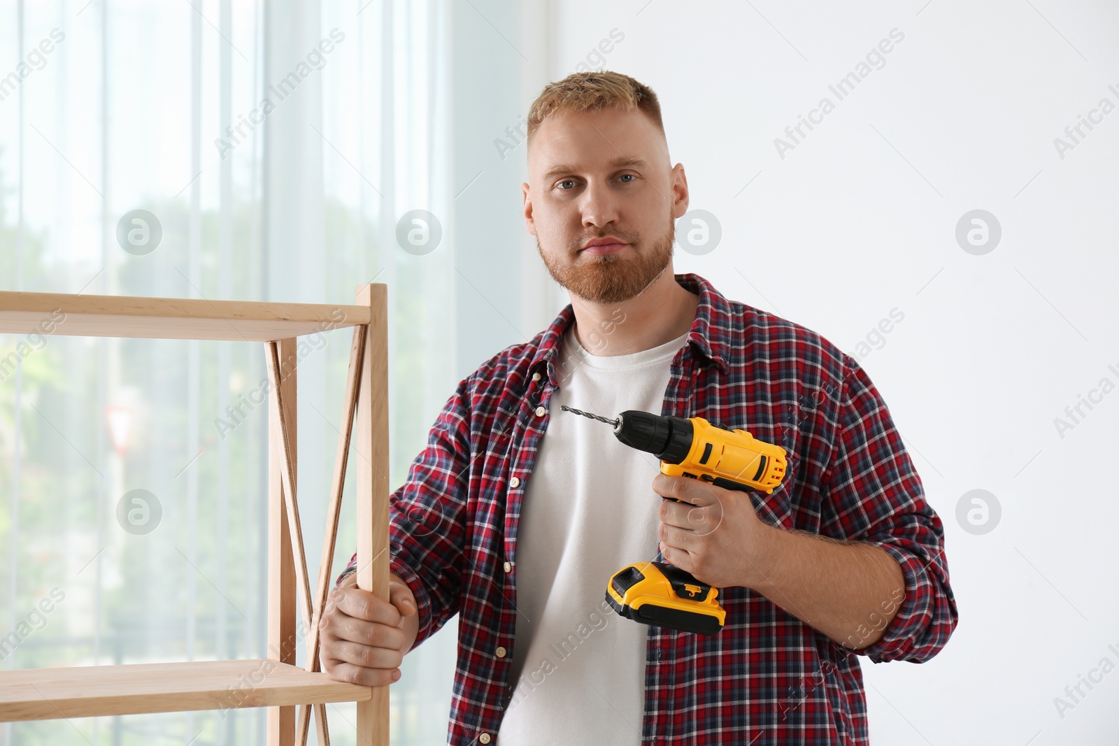 Photo of Man with electric screwdriver at home. Assembling furniture