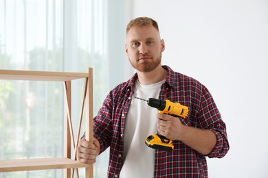 Man with electric screwdriver at home. Assembling furniture