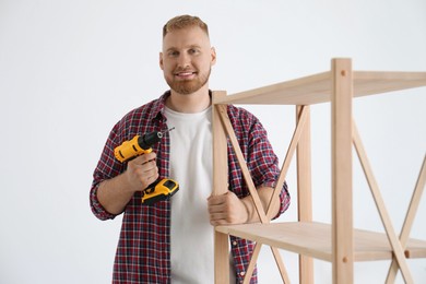 Photo of Man with electric screwdriver at home. Assembling furniture