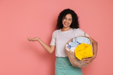 Photo of Happy woman with basket full of laundry on pink background