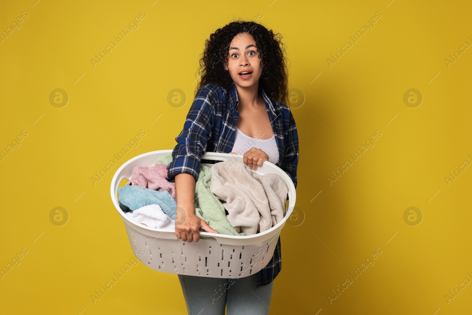 Photo of Shocked woman with basket full of laundry on yellow background