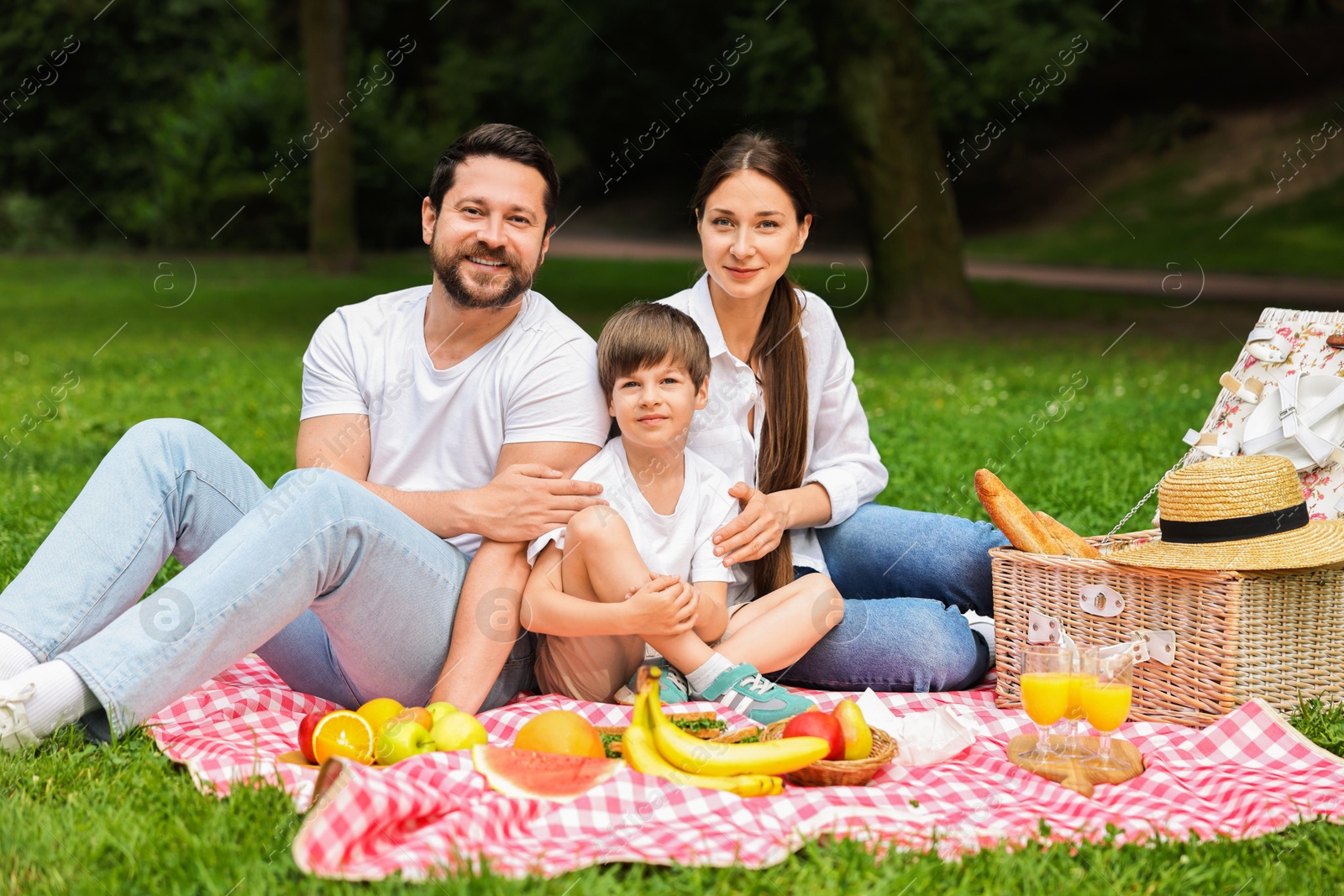 Photo of Family picnic. Happy parents and their son spending time together in park