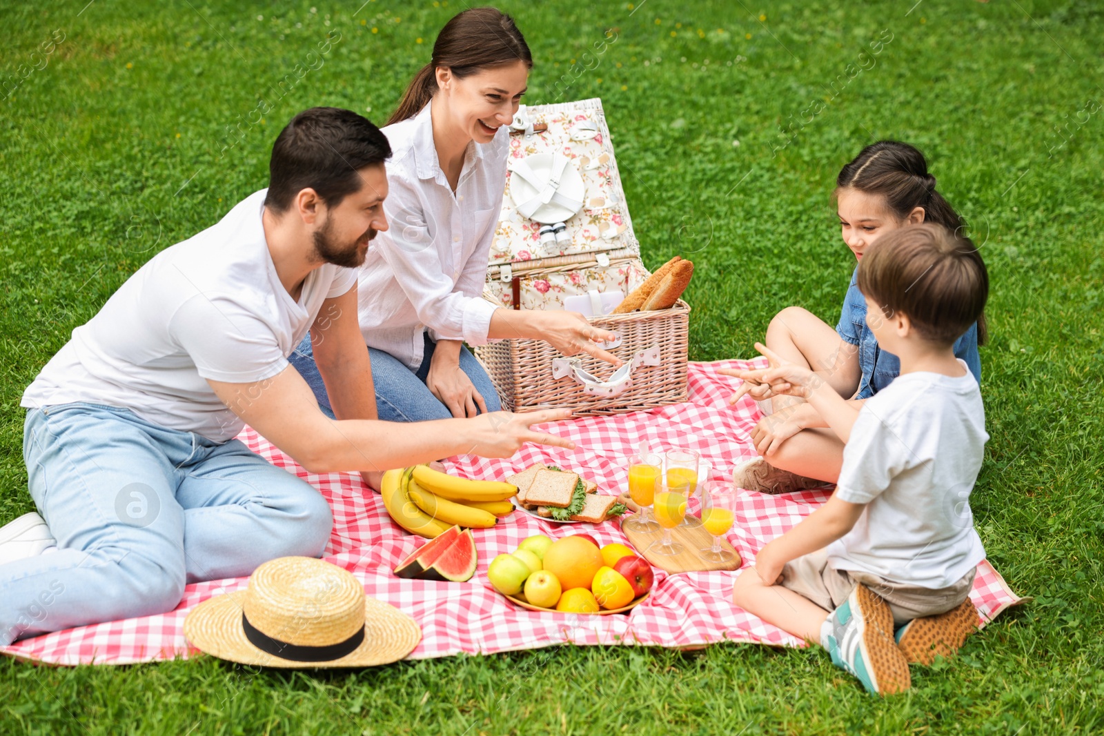 Photo of Happy family playing rock, paper and scissors during picnic in park