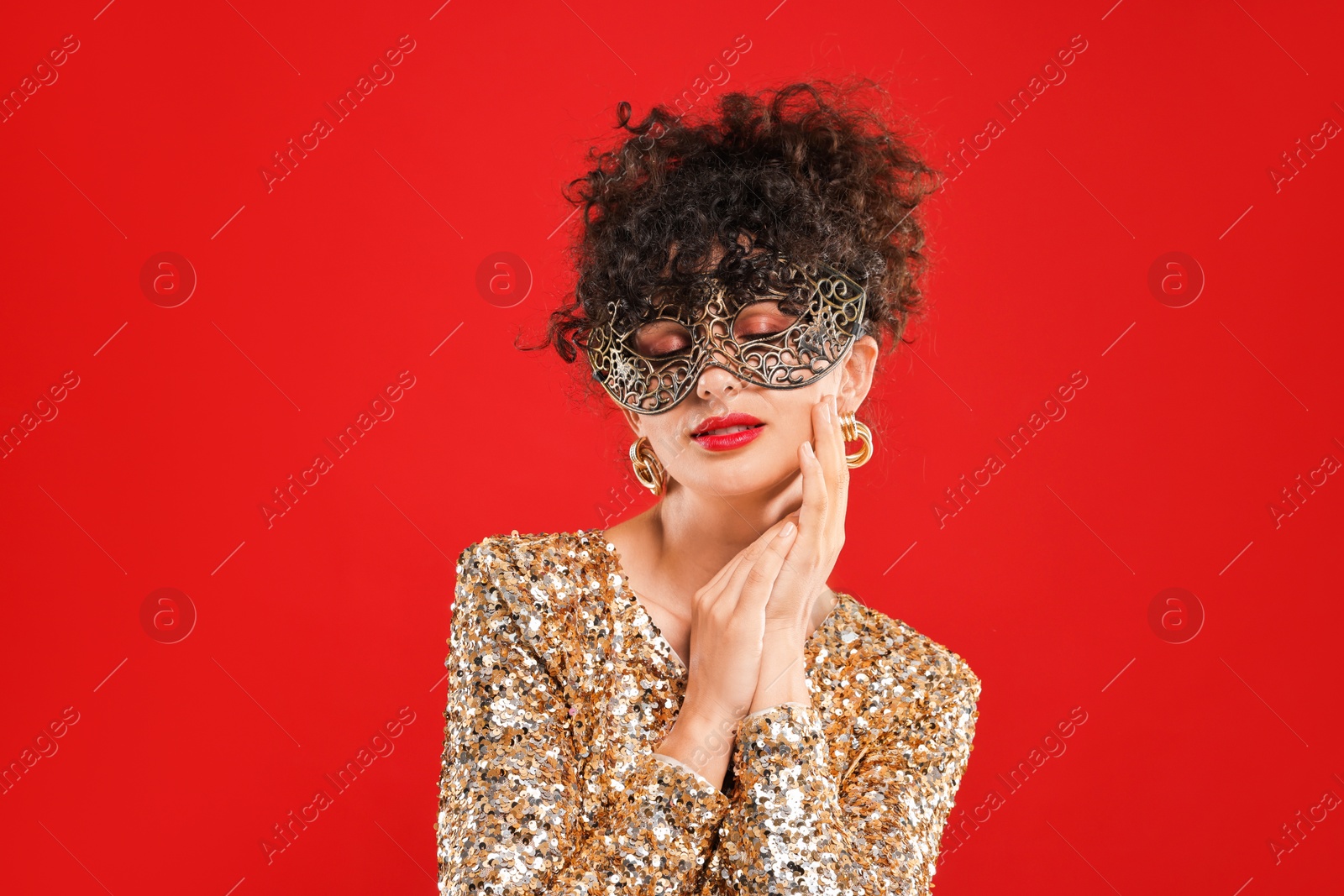 Photo of Beautiful young woman with carnival mask on red background