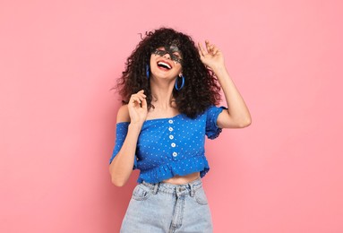 Happy young woman wearing carnival mask on pink background