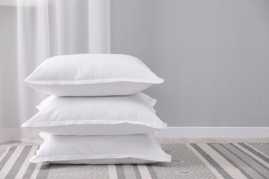 Stack of white pillows on floor indoors. Space for text