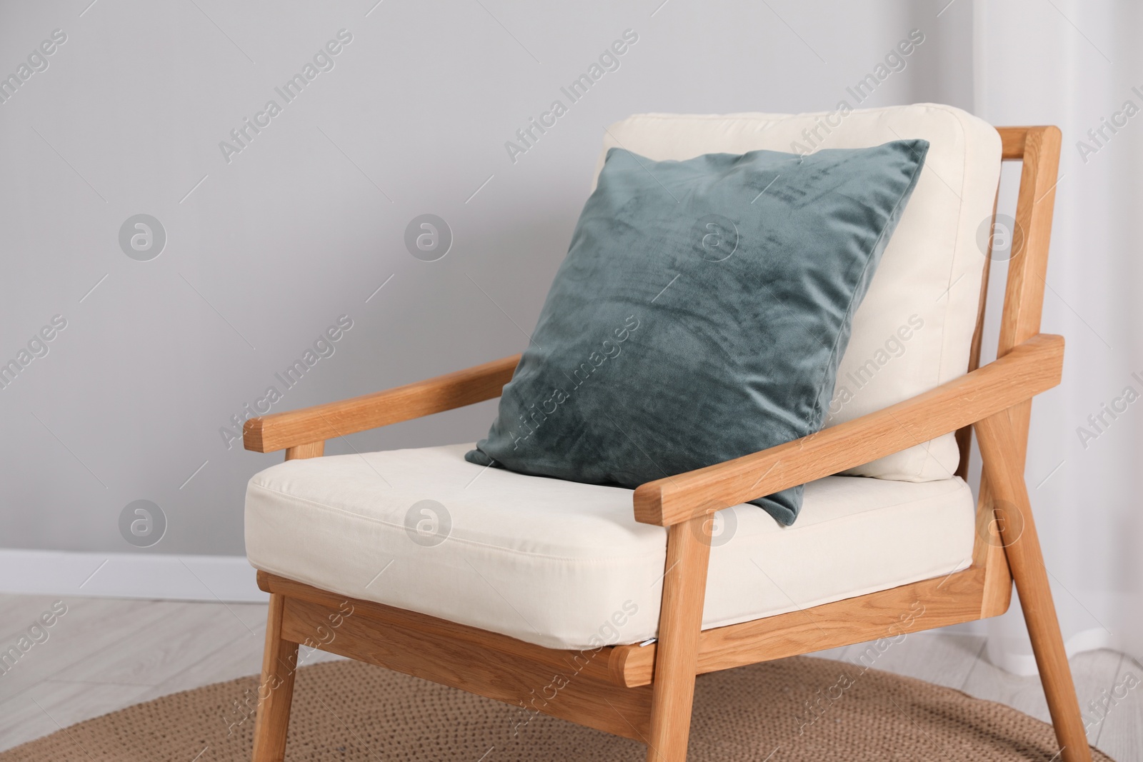 Photo of Soft armchair with pillow on carpet indoors