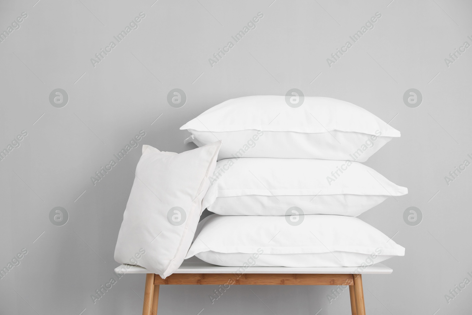 Photo of Stack of pillows on bench against grey wall