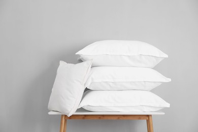 Photo of Stack of pillows on bench against grey wall