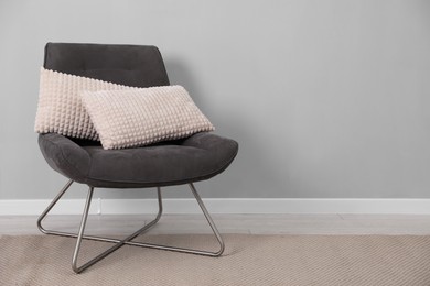 Photo of Soft armchair with pillows on floor indoors. Space for text