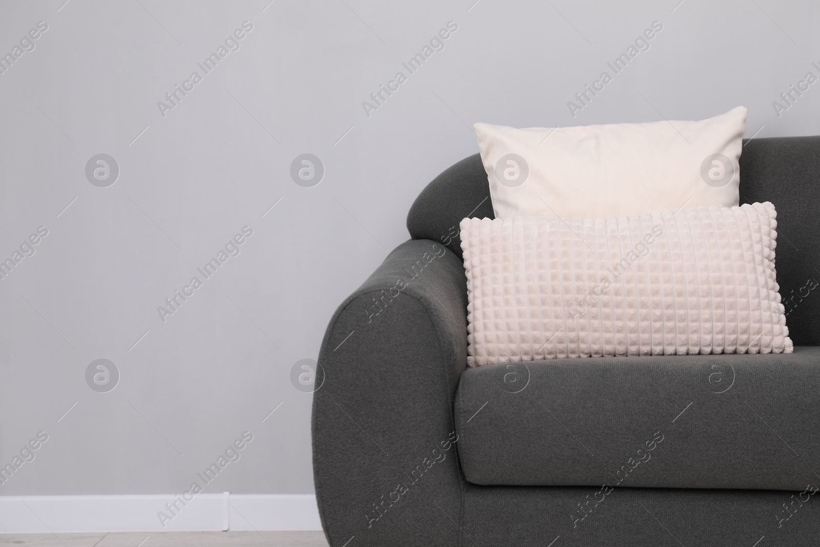 Photo of Soft sofa with pillows on floor indoors. Space for text