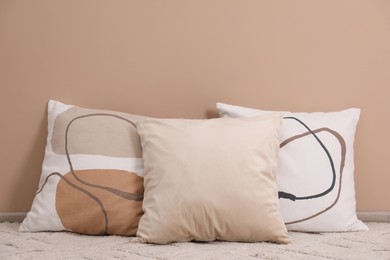 Photo of Soft pillows on floor near beige wall