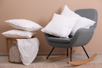 Photo of Pillows, armchair, storage basket and blanket near beige wall