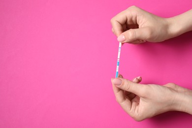 Photo of Woman holding pregnancy test on pink background, top view. Space for text