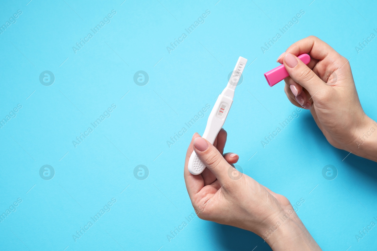 Photo of Woman holding pregnancy test on light blue background, above view. Space for text