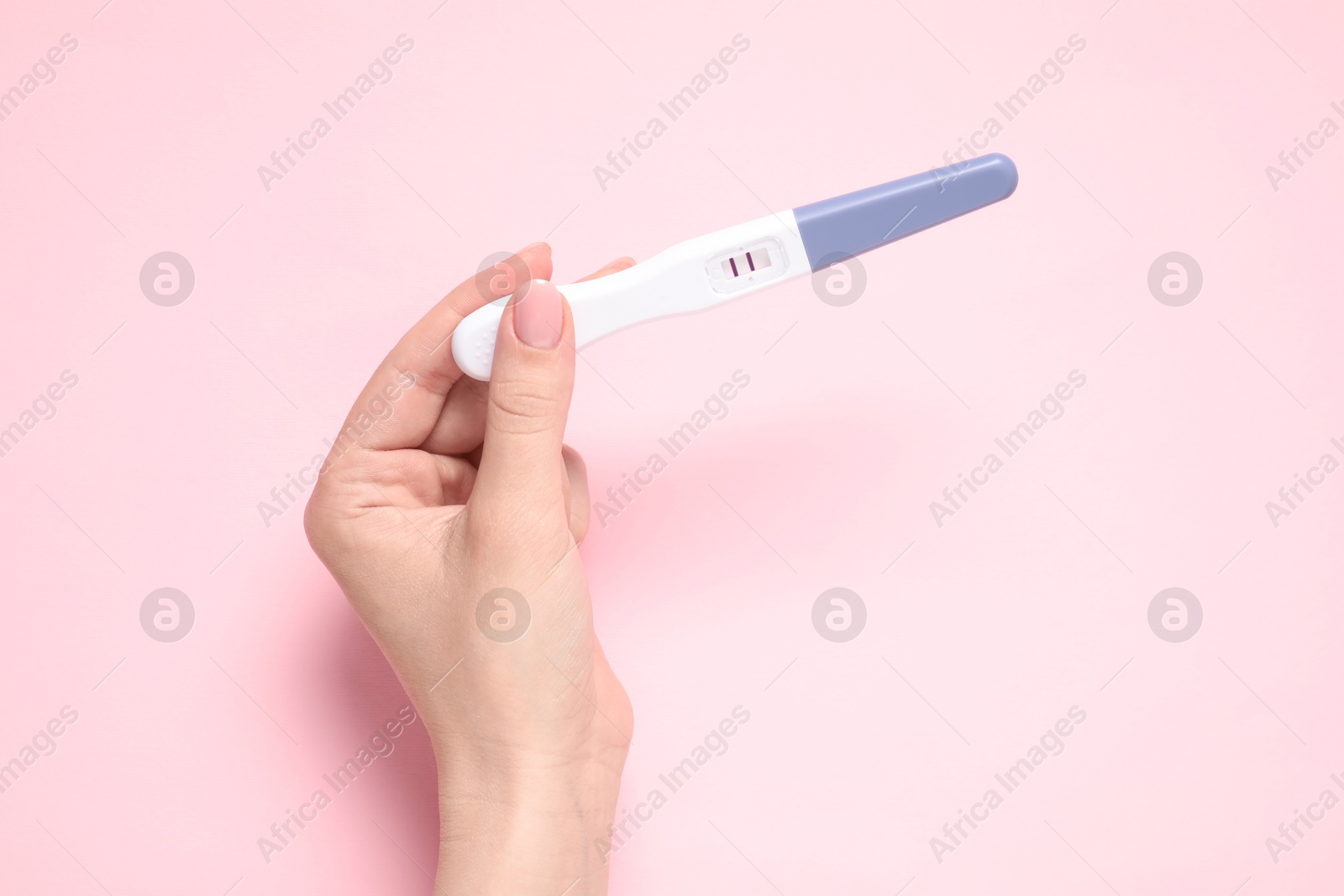 Photo of Woman holding pregnancy test on pink background, top view. Space for text