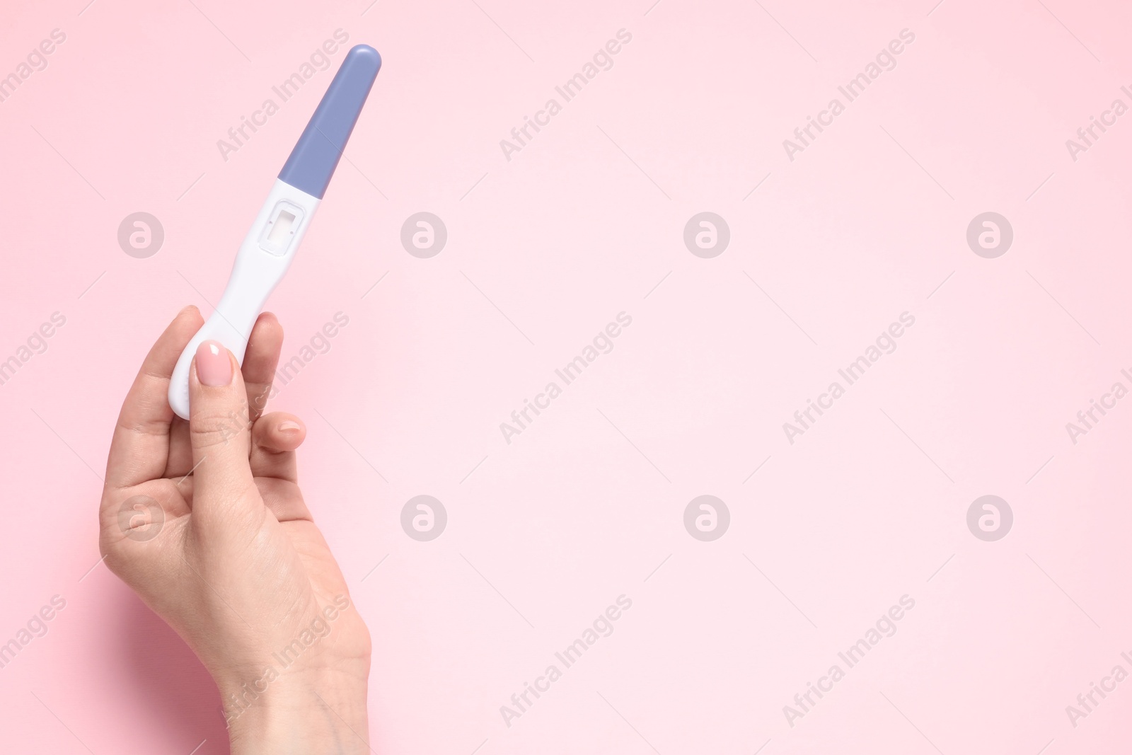 Photo of Woman holding pregnancy test on pink background, top view. Space for text