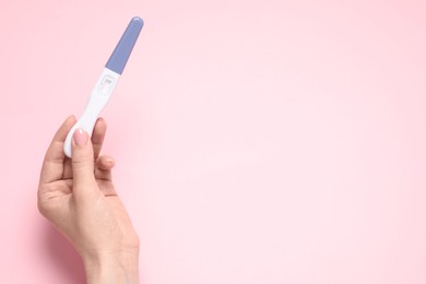 Photo of Woman holding pregnancy test on pink background, top view. Space for text