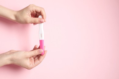 Photo of Woman holding pregnancy test on pink background, top view. Space for text