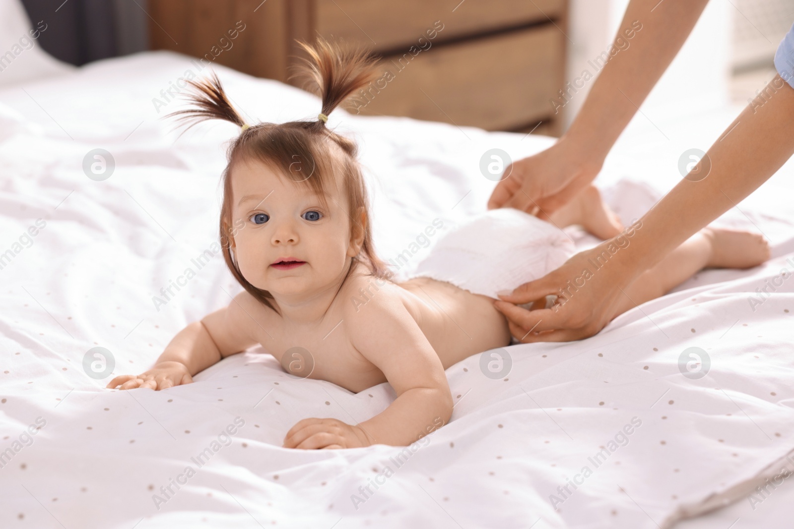 Photo of Mother changing her baby's diaper on bed, closeup