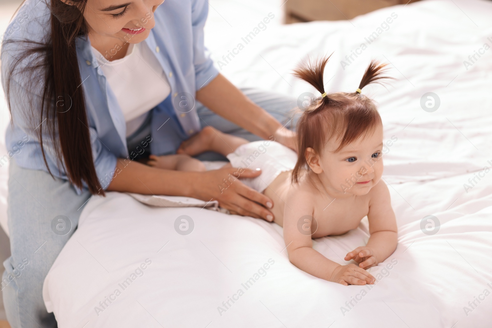 Photo of Mother changing her baby's diaper on bed