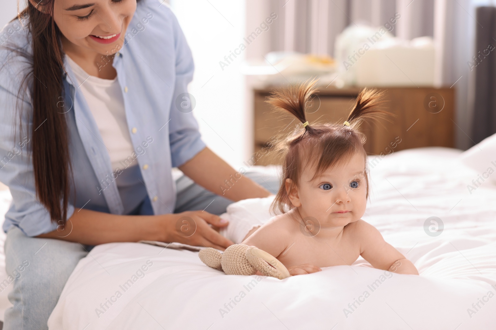 Photo of Mother changing her baby's diaper on bed