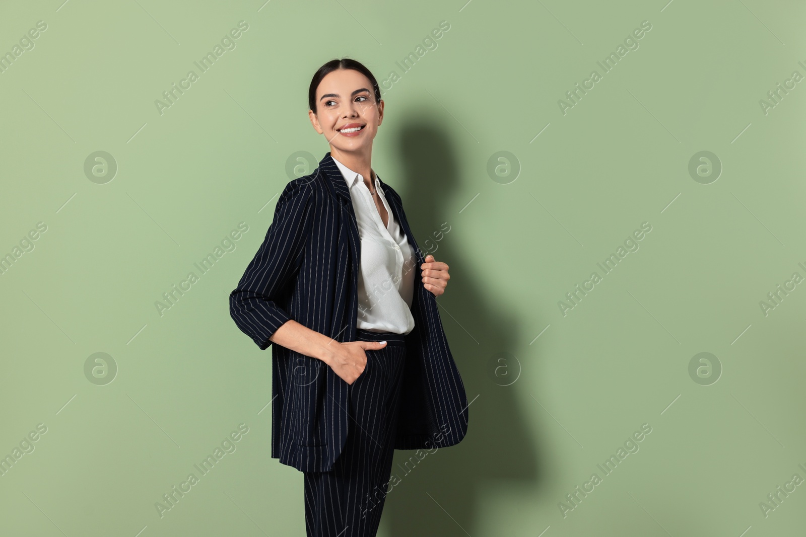 Photo of Beautiful woman in black striped suit on green background