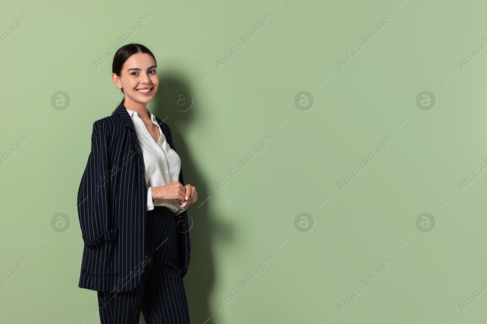 Photo of Beautiful woman in black striped suit on green background, space for text