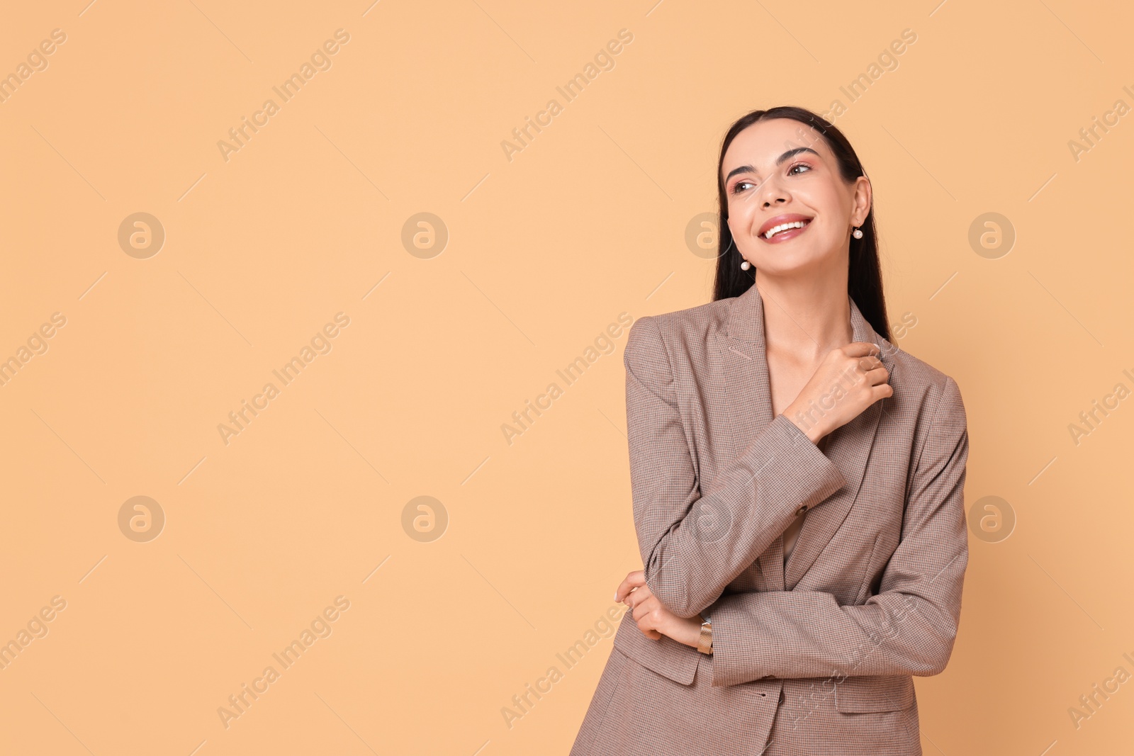 Photo of Beautiful woman in stylish jacket on pale orange background, space for text