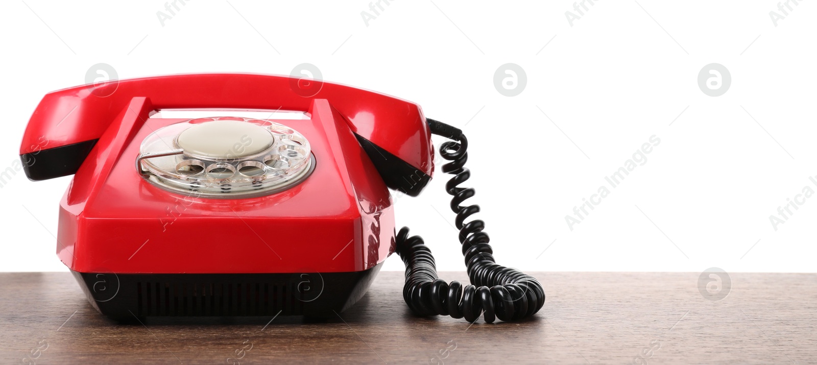 Photo of One red telephone with handset on wooden table against white background