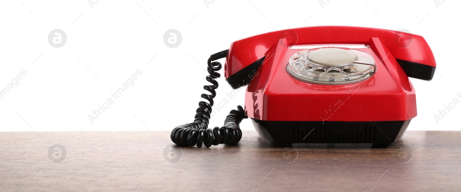 Photo of One red telephone with handset on wooden table against white background