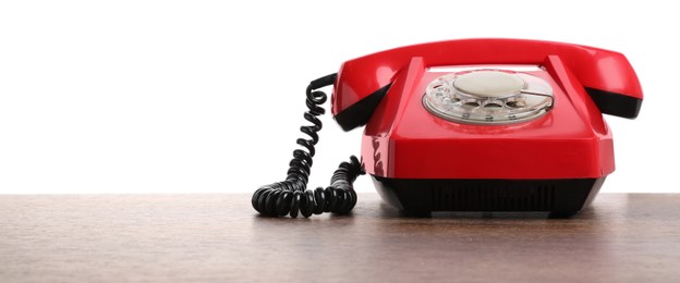 Photo of One red telephone with handset on wooden table against white background