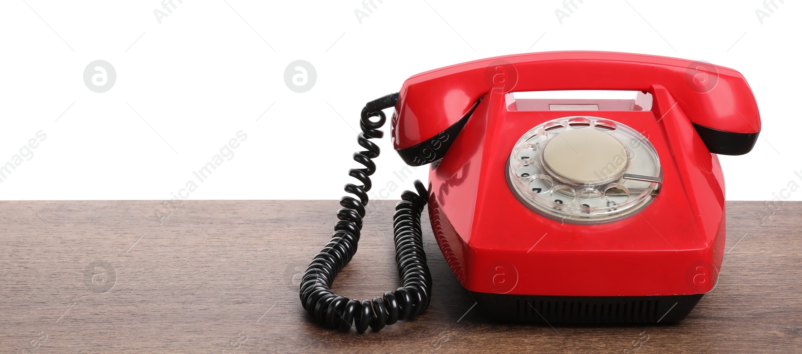 Photo of One red telephone with handset on wooden table against white background