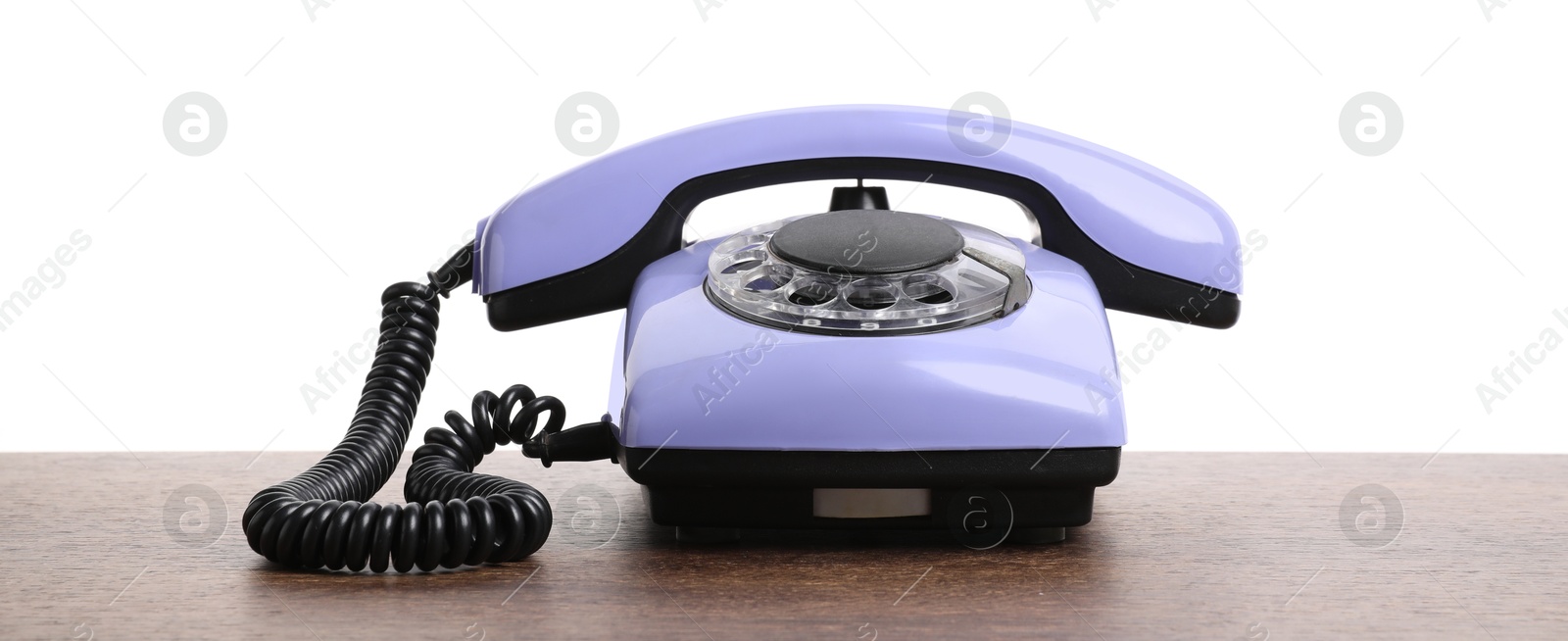 Photo of One violet telephone with handset on wooden table against white background