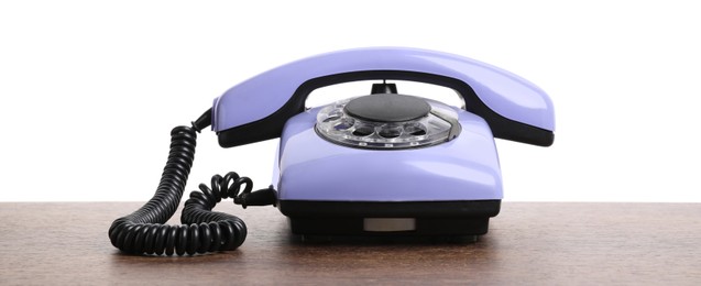 Photo of One violet telephone with handset on wooden table against white background