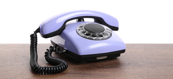 Photo of One violet telephone with handset on wooden table against white background