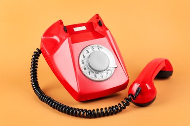 Photo of One red telephone with handset on pale orange background