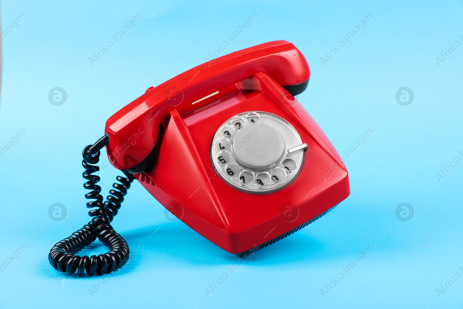 Photo of Red telephone with handset on light blue background